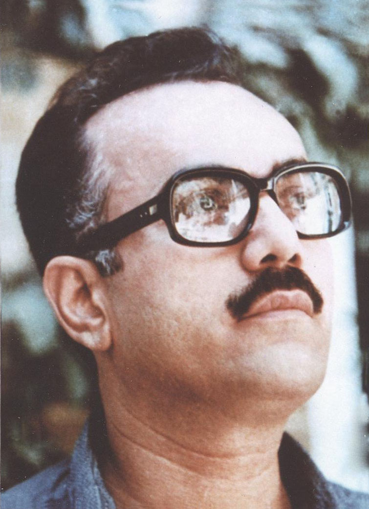 Ahmad Moftizadeh wearing large black-framed glasses and a moustache, looking upward