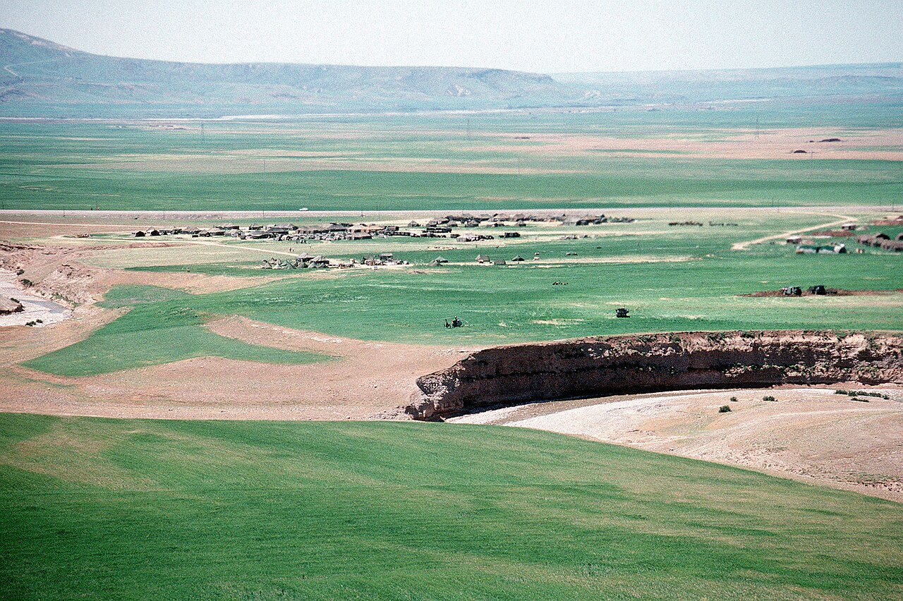 Kurdish refugee tents spread across green fields beside a winding river during the 1991 relief crisis