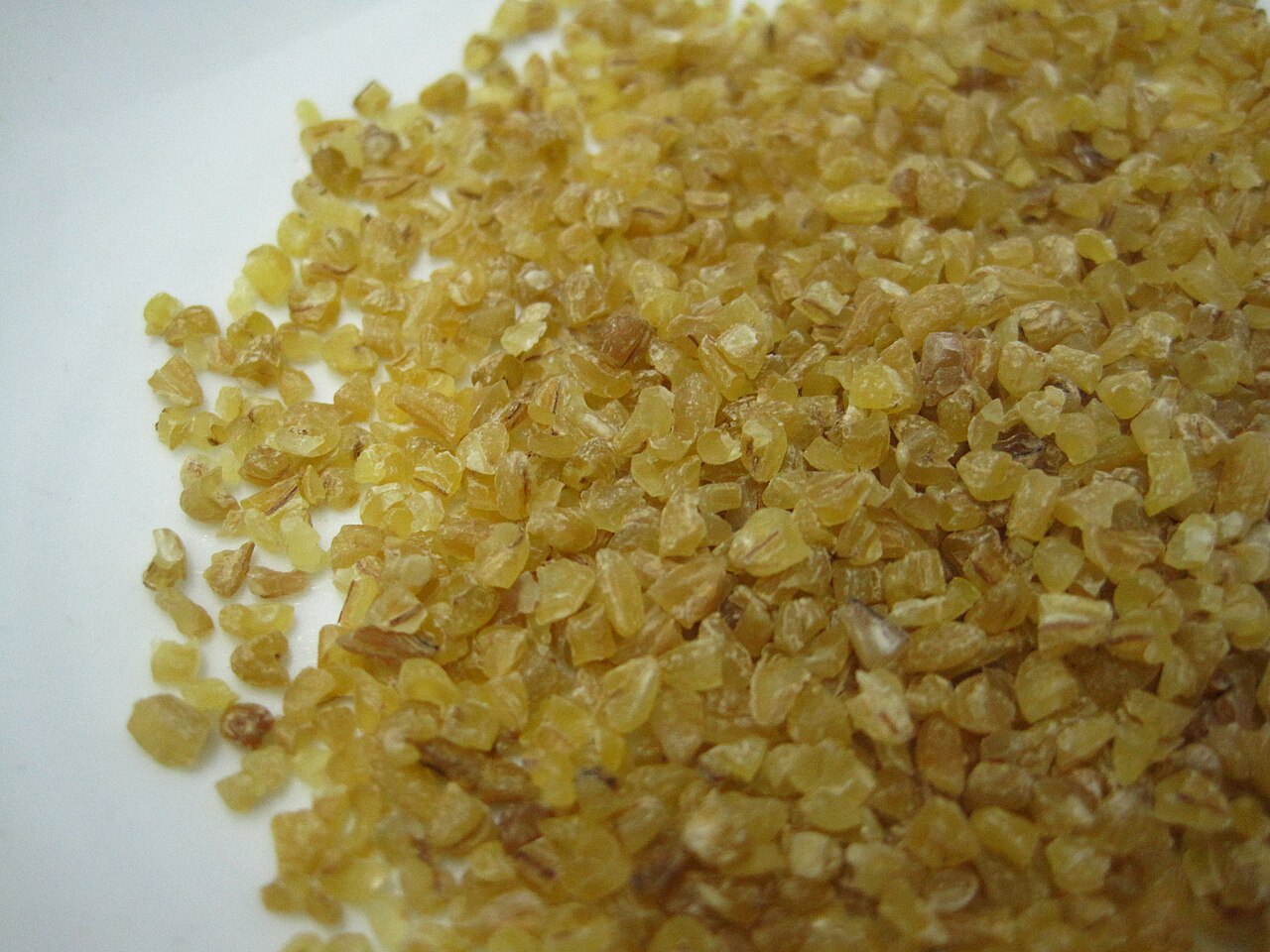 Close-up of golden cracked bulgur grains on a white surface