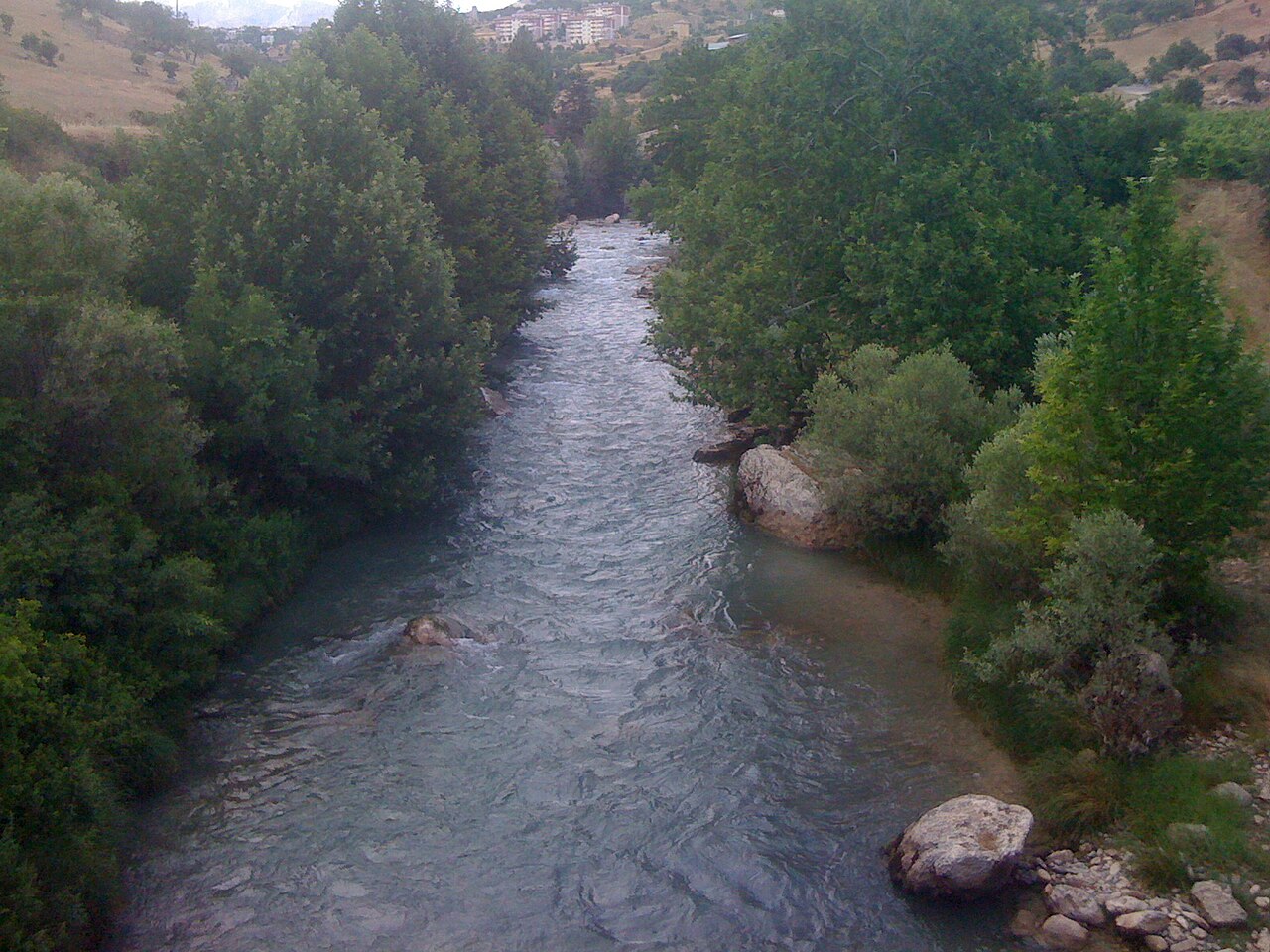 Dersim bölgesindeki Çemişgezek’in tepeleri ve binaları altında ağaçlarla çevrili Tagar Çayı