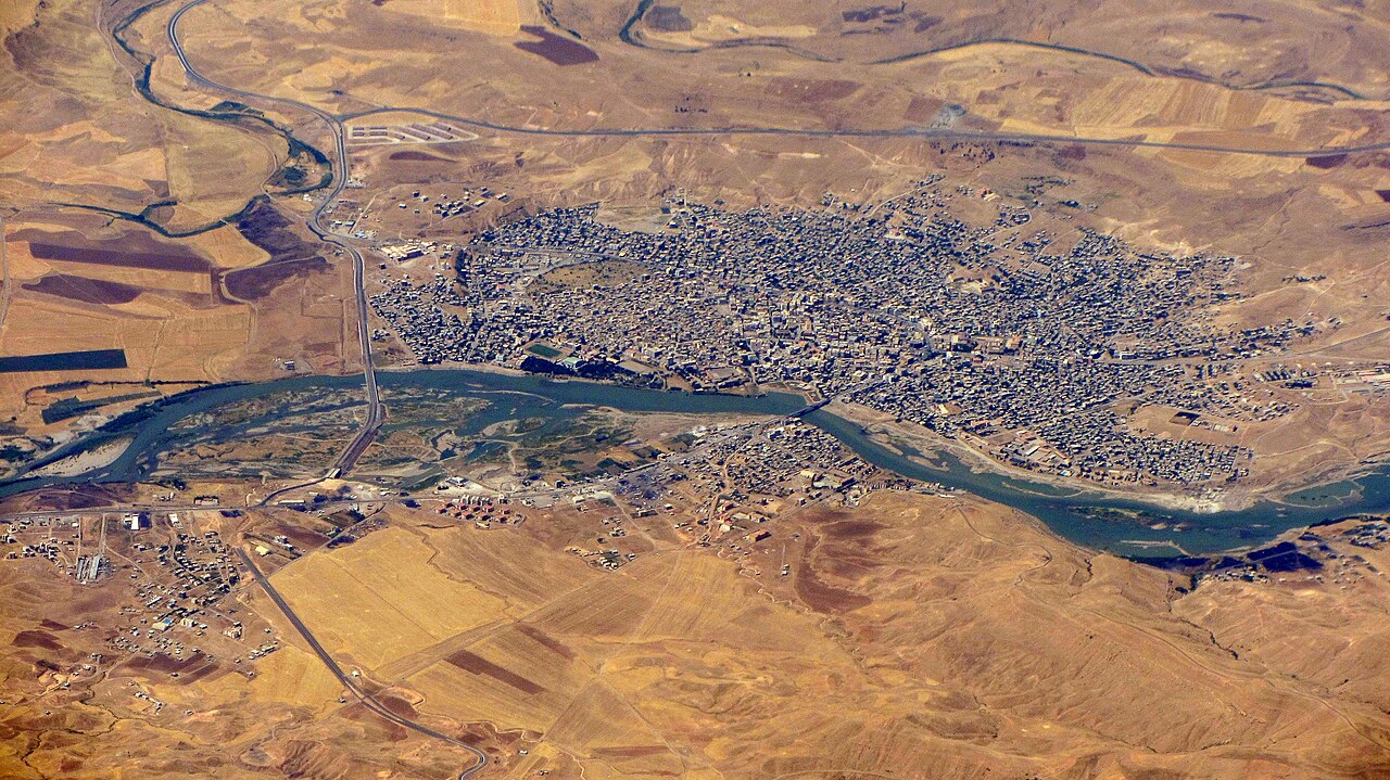 Luftbild von Cizre am gebogenen Tigris mit dichter Bebauung, Brücken, Straßen und trockenen Feldern