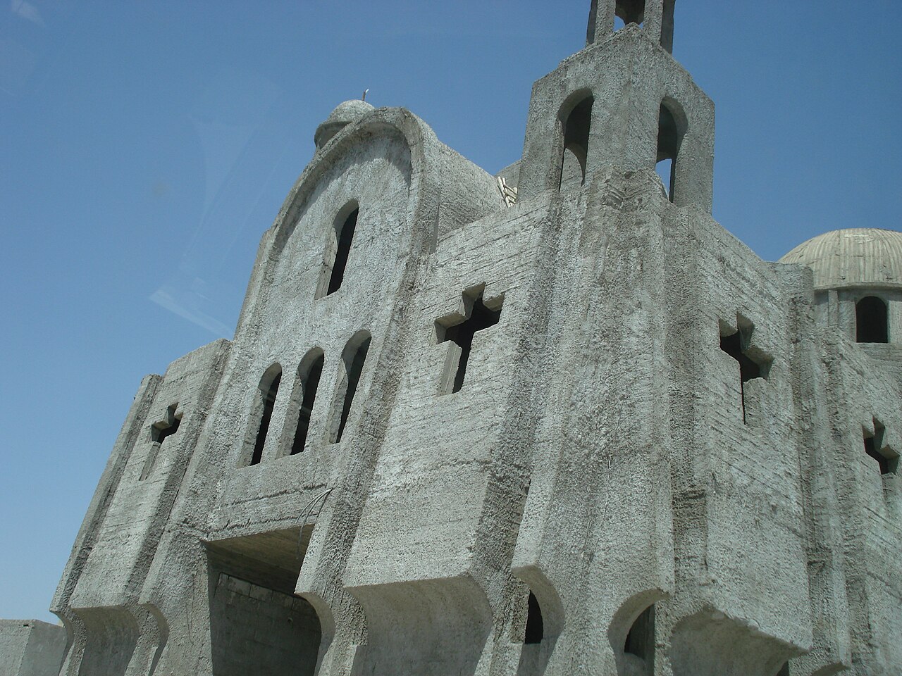 Syrisch-orthodoxe Kirche in Al-Malikiyah 2008 mit hellen Wänden, kreuzförmigen Öffnungen und Türmen vor blauem Himmel