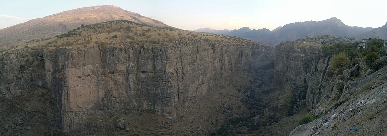 Rawanduz’s deep gorge between sheer rock walls, with a rounded dry hill on the left and houses along the right rim