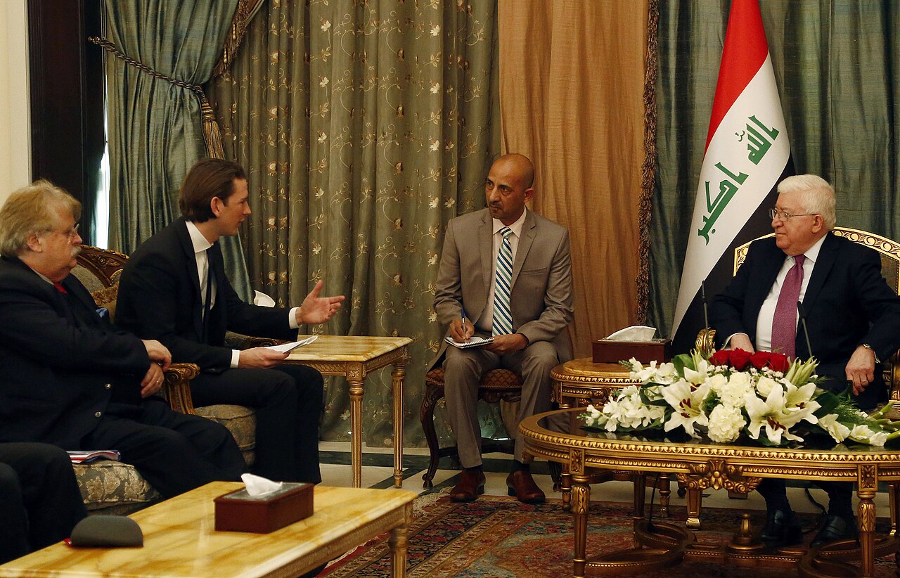 Fuad Masum à droite près du drapeau irakien reçoit Sebastian Kurz ; un participant prend des notes