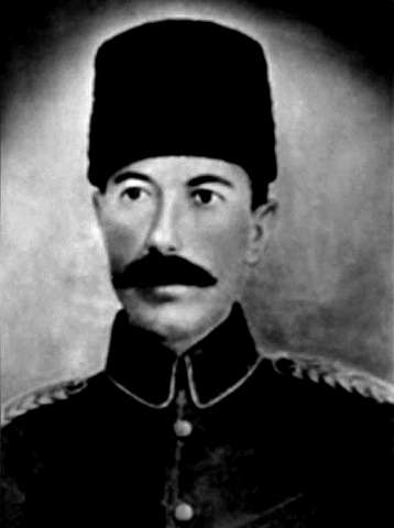 Portreya reş û spî ya Xalid Begê Cibrî bi kumê dirêj ê reş, unîforma leşkerî û simbêlan