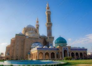 Jalil Khayat Mosque with a large central dome, smaller domes, a tall minaret and an arcaded entrance beside a garden