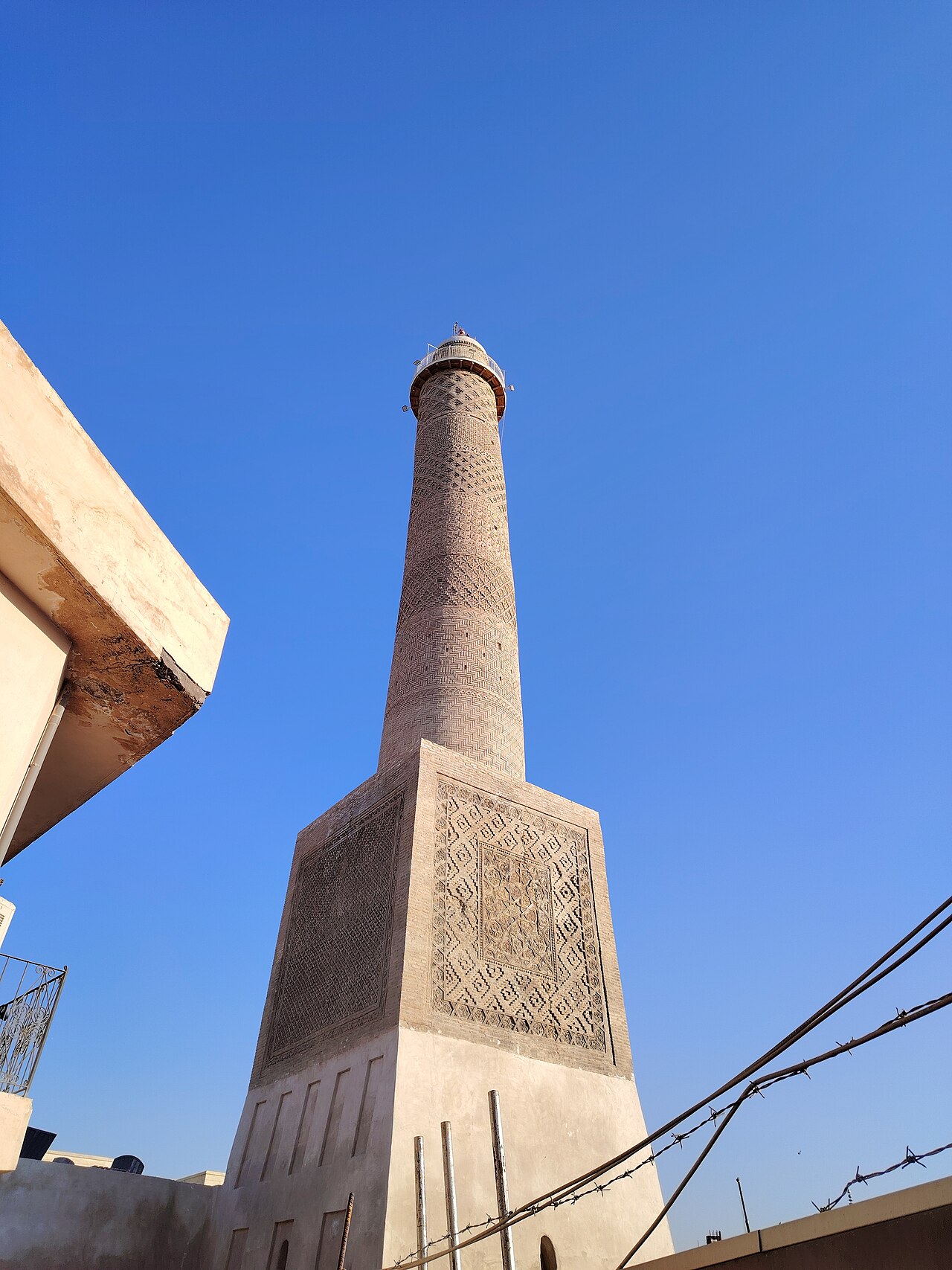 The rebuilt al-Hadba minaret rises from a decorated square brick base into a clear blue sky in Mosul