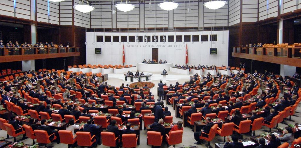 Members of Turkey’s parliament seated in curved rows of orange chairs facing the raised speaker’s platform in the assembly chamber