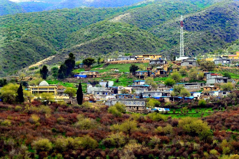 Häuser, Bäume und ein Sendemast am Hang von Rawanduz unter grünen Berghängen
