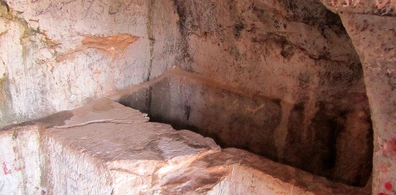 Interior of the Darband rock tomb at Sahneh, showing carved stone platforms and recessed spaces in the rock