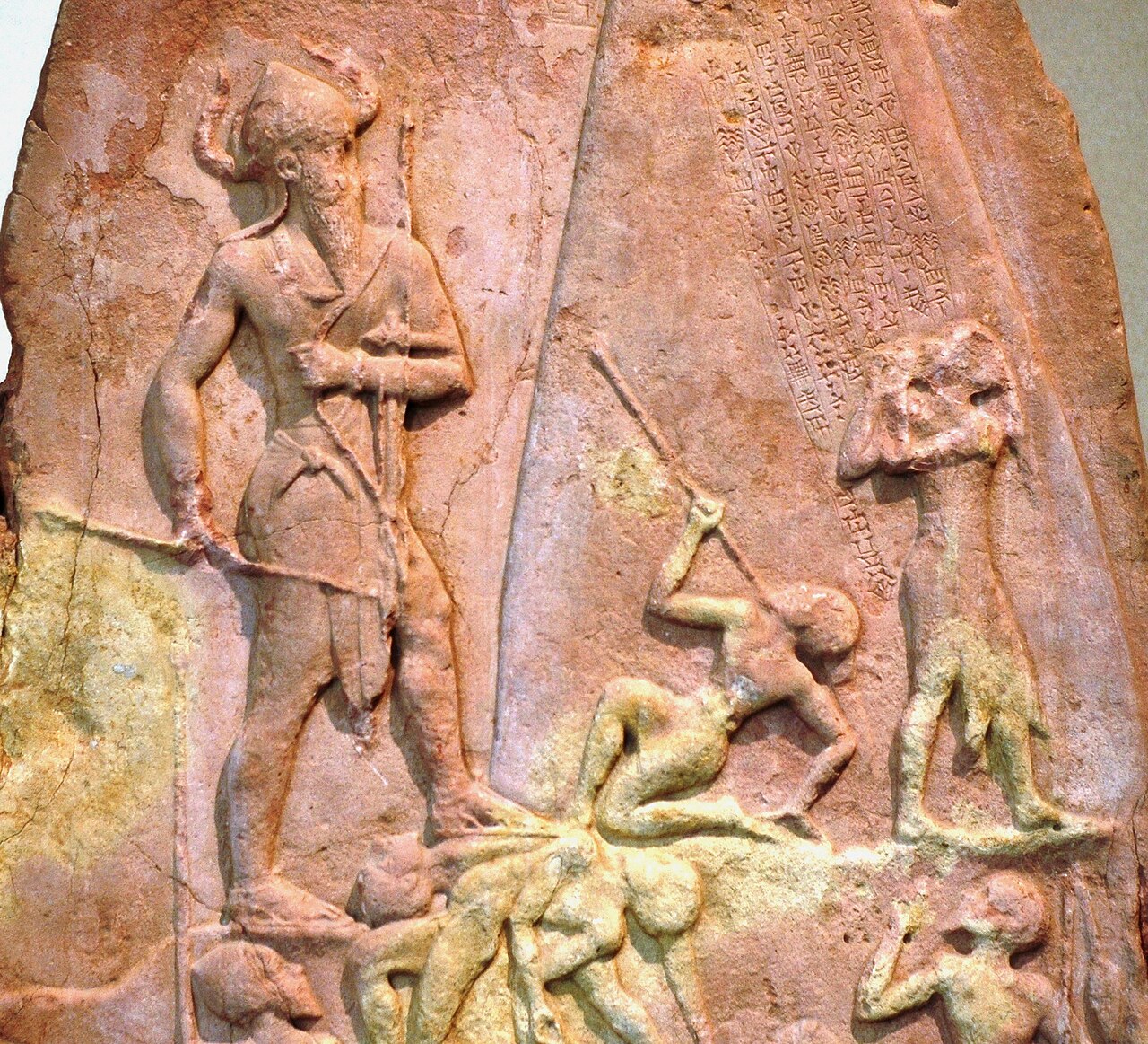 Détail du relief avec Naram-Sin armé à gauche, personnages vaincus et inscription cunéiforme ajoutée au-dessus