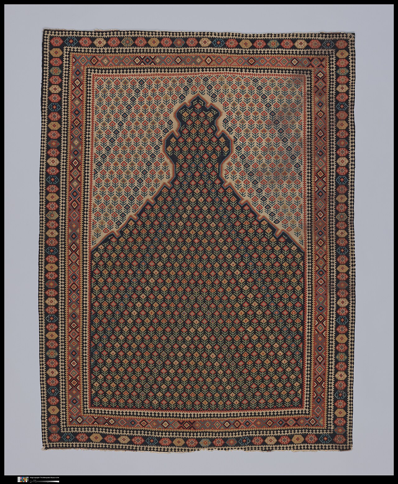 Senneh prayer rug with a dark stepped prayer niche, densely repeated flowers and multicoloured geometric borders on a pale ground