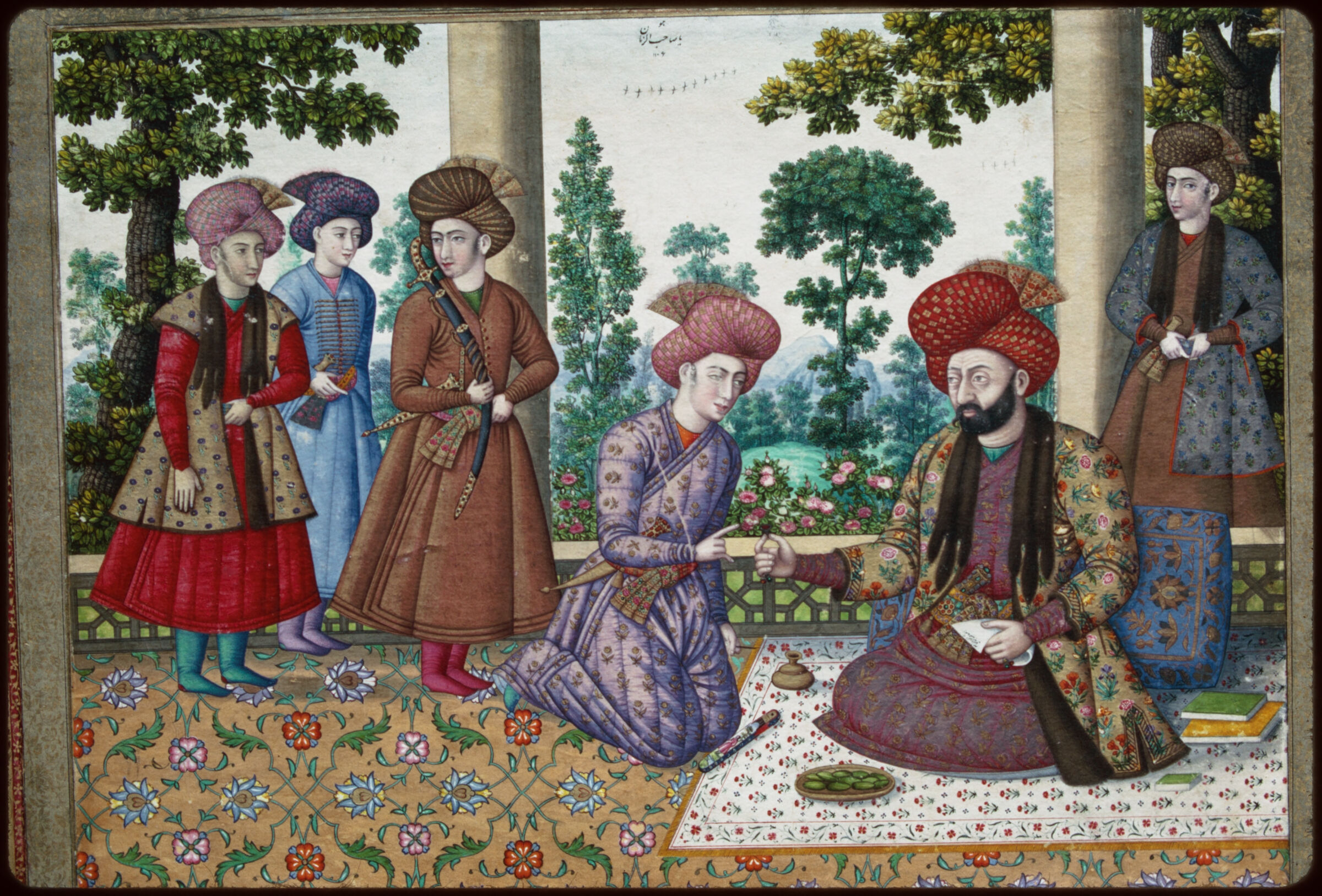 رسم صفوي لمسؤول ملتحٍ يقدم خاتماً لشاب راكع، مع أربعة مرافقين وكتب وأشجار على شرفة