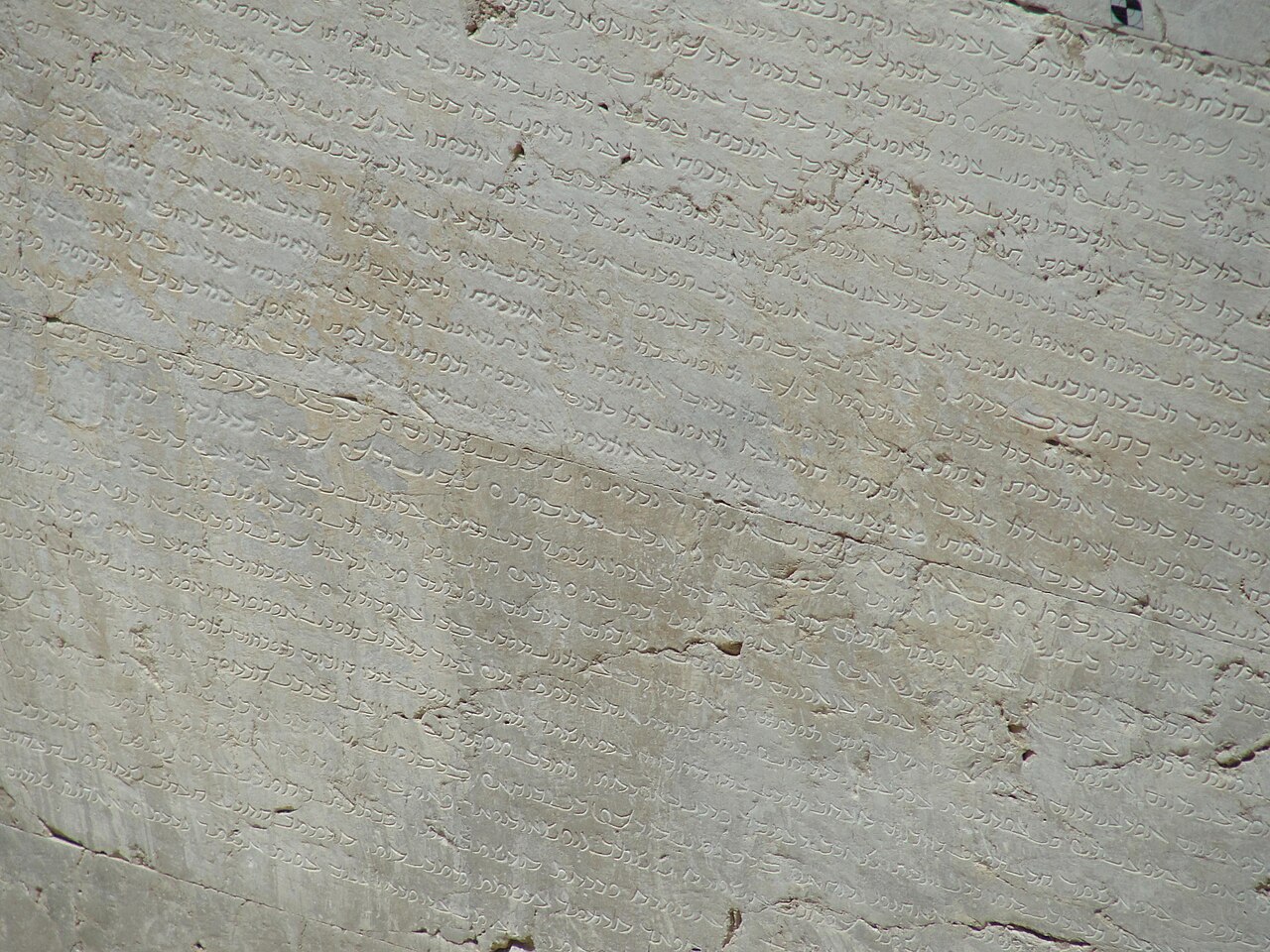 Lignes d’une inscription parthe gravées dans une pierre claire altérée et traversées de fissures