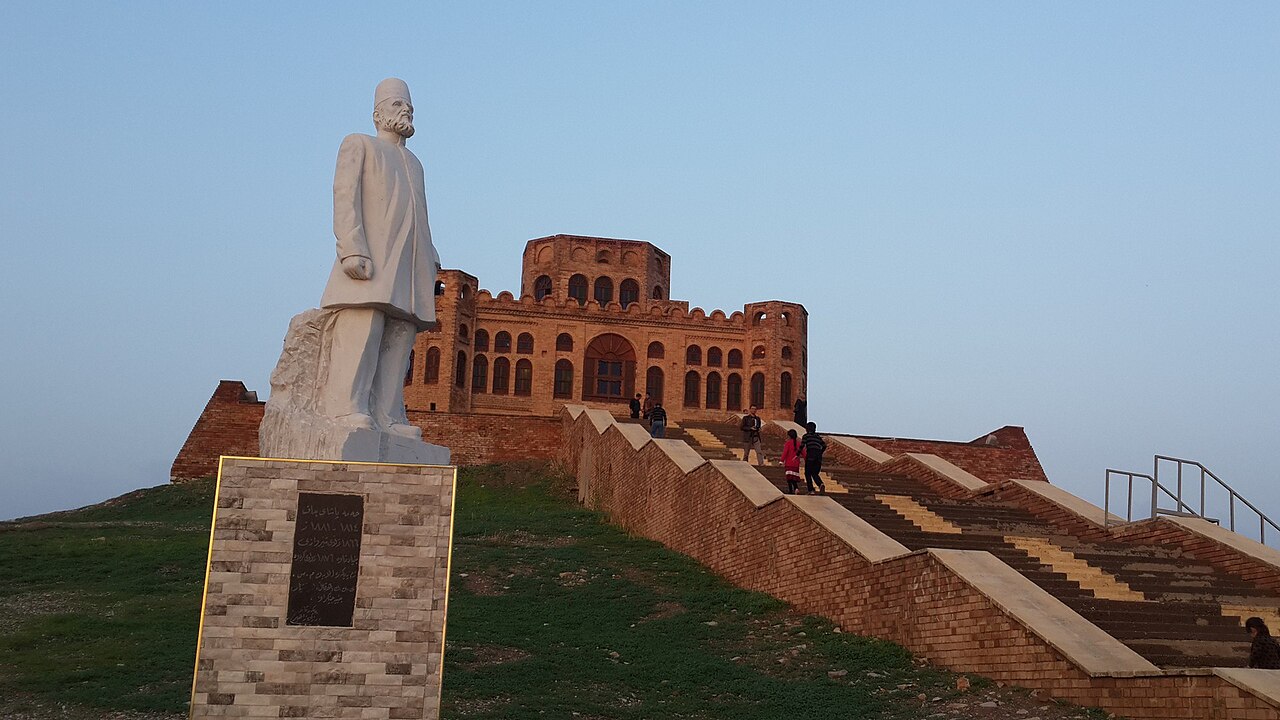 Sherwana Castle above a broad stairway, with a statue of Hama Pasha Jaf in the foreground