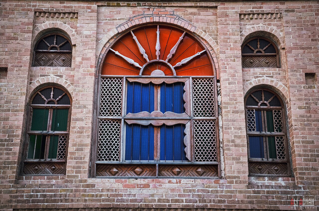 Decorative wooden windows with coloured panels and arched brick surrounds at Sherwana Castle