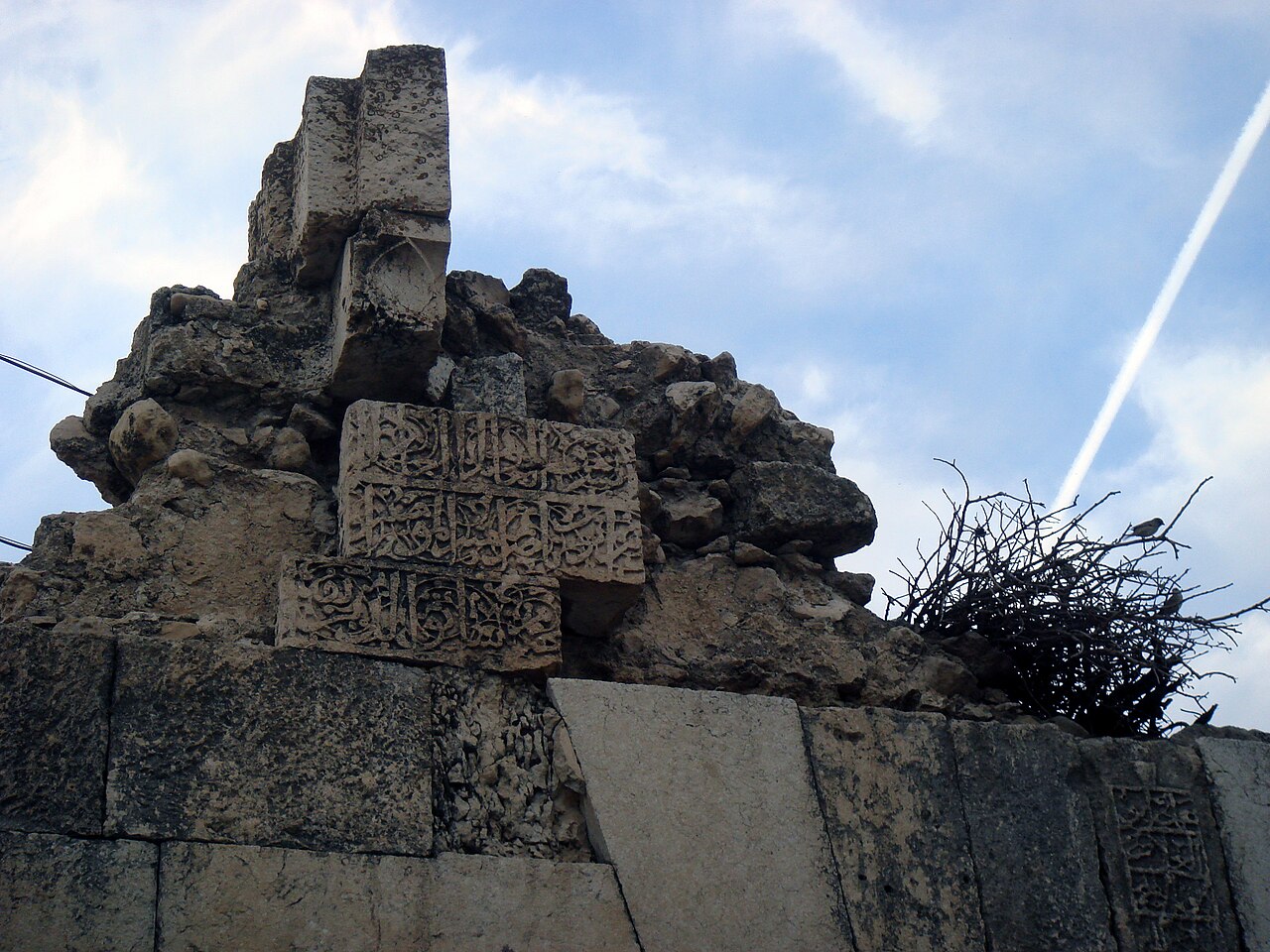 Weathered stonework and carved Arabic inscriptions at the Qulfa gate in Farqîn
