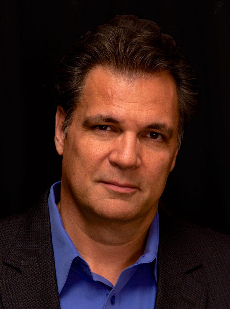 Portrait of Stephen Mansfield in a blue shirt and dark jacket against a black background