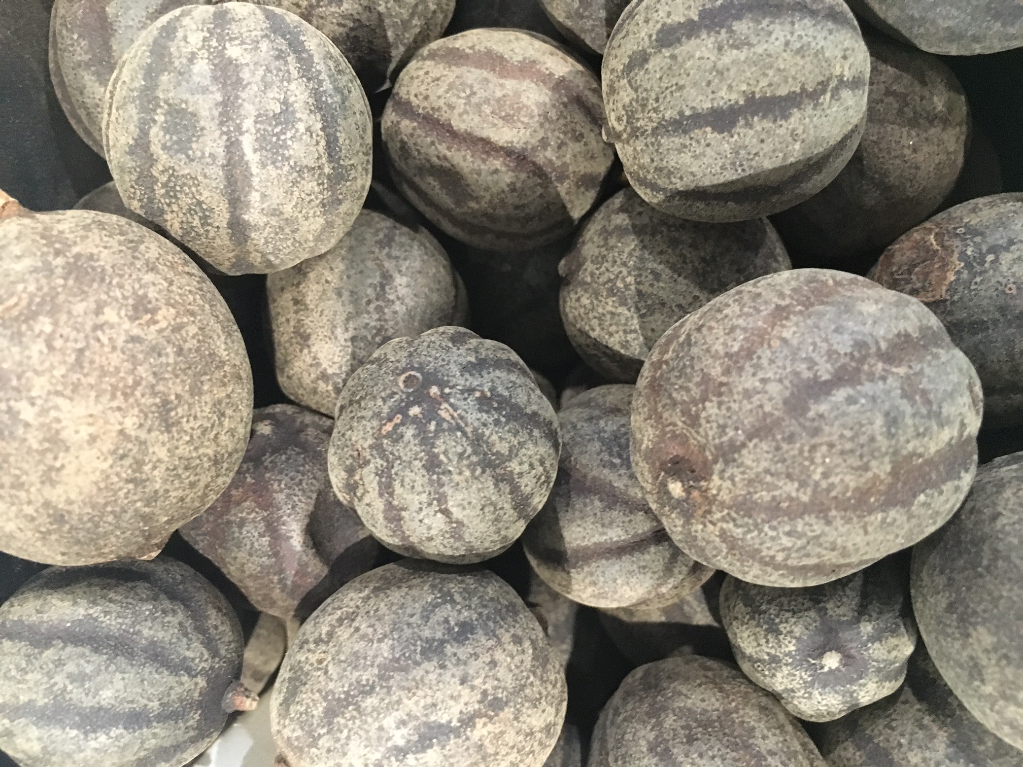 Whole dried limes with mottled brown skins piled together in a close-up photograph