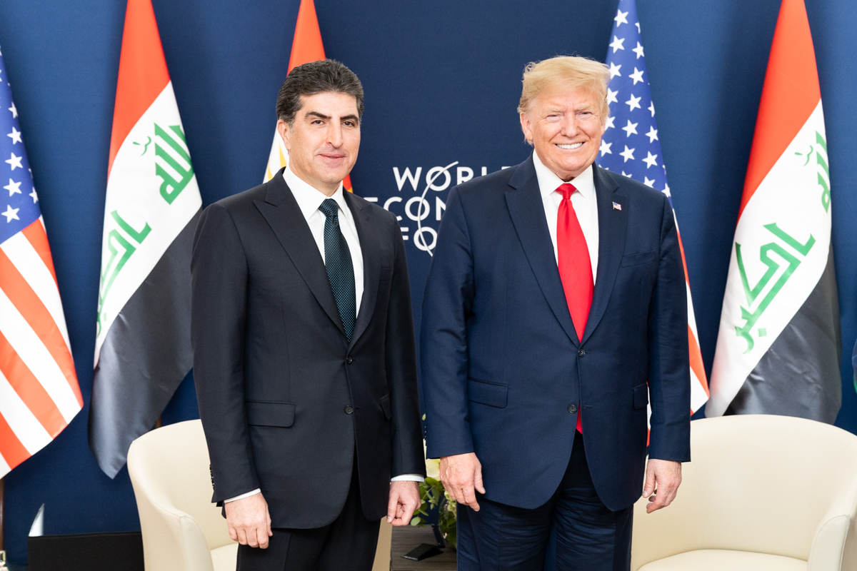 Nechirvan Barzani and Donald Trump standing beside each other before Iraqi and United States flags at Davos